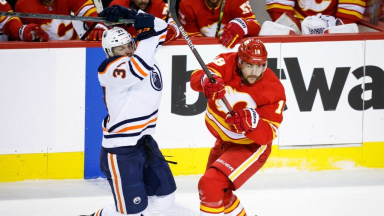 Edmonton Oilers' Warren Foegele, left, is checked by Calgary Flames' Ryan Carpenter during first period NHL hockey action in Calgary, Saturday, March 26, 2022. (Jeff McIntosh/CP)