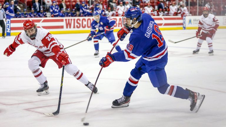 Shay Donovan (28) tries to block a slap shot from U-18 forward Cutter Gauthier (19) during a college hockey match between the University of Wisconsin Badgers and the U.S. National Under-18 Team on December 2, 2021 at the Kohl Center in Madison, WI. (Photo by Lawrence Iles/Icon Sportswire via Getty Images)