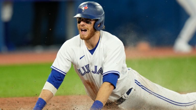 Toronto Blue Jays catcher Danny Jansen (9) celebrates as he slides into home plate for the go ahead run during sixth inning American League baseball action against the Texas Rangers in Toronto, Friday, April 8, 2022. (Frank Gunn/CP)