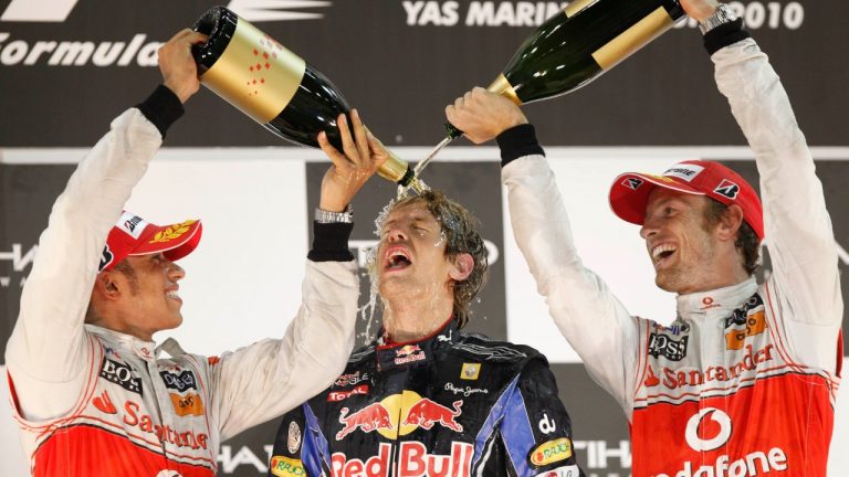 FILE - McLaren Mercedes driver Lewis Hamilton of Britain, left, and his teammate driver Jenson Button spray rose water on Formula One 2010 World Champion Red Bull driver Sebastian Vettel of Germany after he won the Emirates Formula One Grand Prix, in Abu Dhabi, UAE, Sunday, Nov.14, 2010. (Luca Bruno/AP)