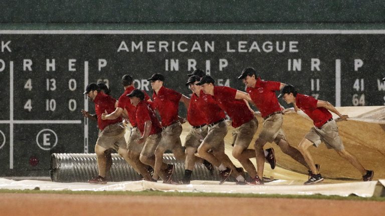 Grounds crew workers spread the tarp over the field as heavy rains fall at Fenway Park in Boston. (Charles Krupa/AP)