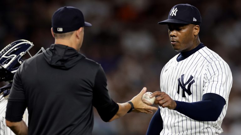 New York Yankees pitcher Aroldis Chapman, right, hands the ball to manager Aaron Boone during the ninth inning of a baseball game against the Toronto Blue Jays, Friday, Aug. 19, 2022, in New York. (Adam Hunger/AP)