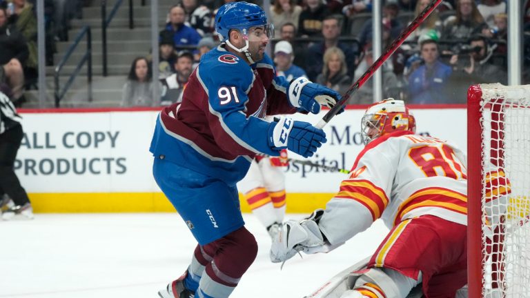 Colorado Avalanche centre Nazem Kadri, left, pursues the puck as Calgary Flames goaltender Dan Vladar defends in the third period of an NHL hockey game Sunday, March 13, 2022, in Denver. (David Zalubowski/AP)