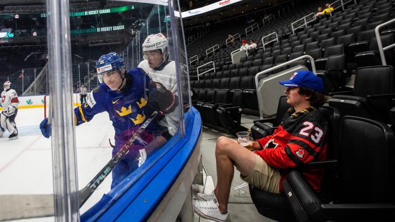 Sweden's Liam Ohgren (25), checks Switzerland's Nick Meile (2) as a fan watches during second period IIHF World Junior Hockey Championship action in Edmonton on Wednesday, August 10, 2022. (Jason Franson/CP)