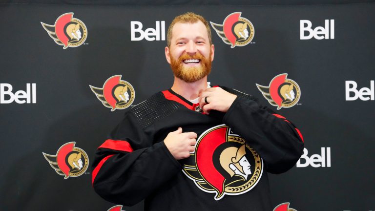 Veteran forward Claude Giroux pulls on an Ottawa Senators sweater in Ottawa on Wednesday, July 13, 2022, after signing a 3-year contract with the team. (Sean Kilpatrick/CP)