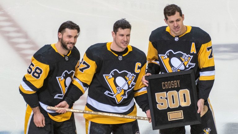 Pittsburgh Penguins center Sidney Crosby, center, is presented with a gold stick and plaque by Kris Letang, left, and Evgeni Malkin, right, in honor of his 500th career goal before the start of an NHL hockey game against the Carolina Hurricanes and Pittsburgh Penguins on Sunday, Feb. 20, 2022, in Pittsburgh. Crosby scored goal number 500 during a game on Feb. 15, 2022, against the Philadelphia Flyers. (Fred Vuich/AP)