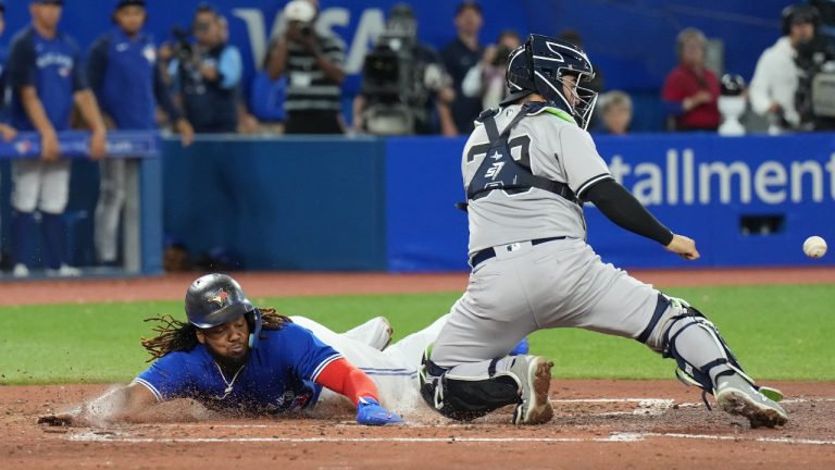 Toronto Blue Jays first baseman Vladimir Guerrero Jr. (27)slides safely into home plate past New York Yankees catcher Jose Trevino (39) during fourth inning American League MLB baseball action in Toronto on Monday, September 26, 2022. (Nathan Denette/CP)