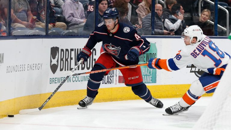 Columbus Blue Jackets' Scott Harrington, left, tries to clear the puck as New York Islanders' Anthony Beauvillier defends during the third period of an NHL hockey game Thursday, Oct. 21, 2021, in Columbus, Ohio. The Blue Jackets won 3-2 in overtime. (Jay LaPrete/AP)