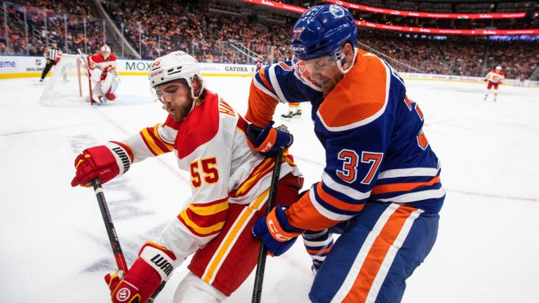 Calgary Flames' Noah Hanifin (55) and Edmonton Oilers' Warren Foegele (37) battle for the puck during second period pre-season action in Edmonton on Friday, September 30, 2022.THE CANADIAN PRESS/Jason Franson