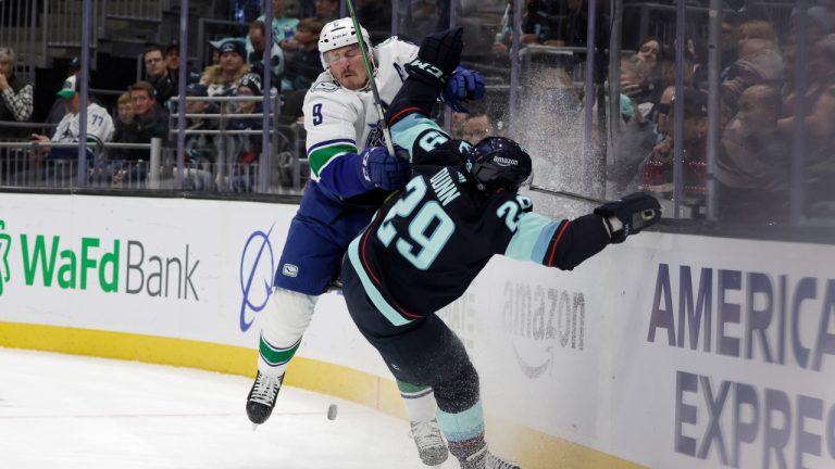 Vancouver Canucks center J.T. Miller (9) colides with Seattle Kraken defenseman Vince Dunn (29) behind the net during the first period of an NHL hockey game. (John Froschauer/AP)