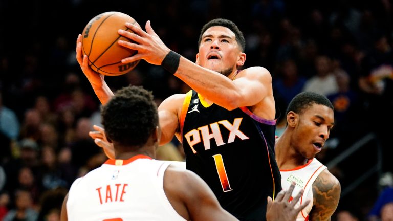 Phoenix Suns' Devin Booker (1) drives to the basket between Houston Rockets' Jae'Sean Tate (8) and Kevin Porter Jr. (3) during the second half of an NBA basketball game, Sunday, Oct. 30, 2022, in Phoenix. (Darryl Webb/AP)