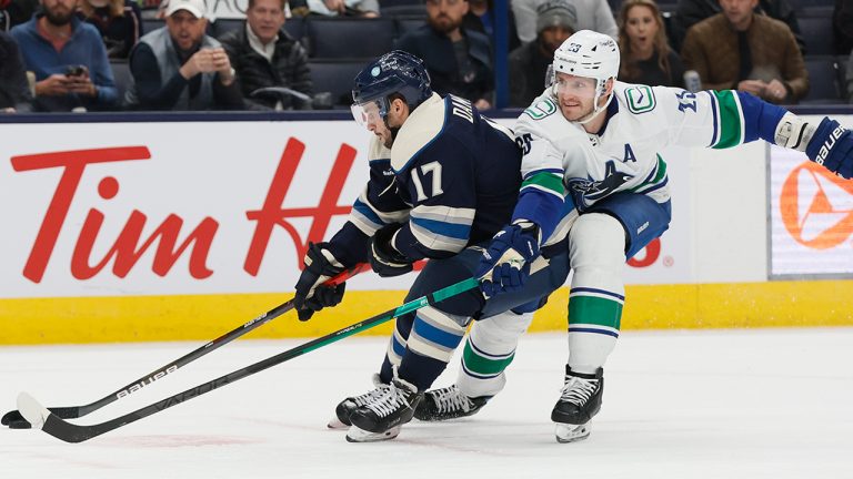 Columbus Blue Jackets' Justin Danforth, left, keeps the puck away from Vancouver Canucks' Oliver Ekman-Larsson during the second period of an NHL hockey game Tuesday, Oct. 18, 2022, in Columbus, Ohio. (Jay LaPrete/AP)