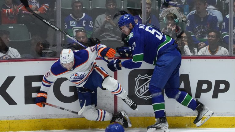 Vancouver Canucks' Tyler Myers, right, checks Edmonton Oilers' Dylan Holloway during the first period of a pre-season NHL hockey game in Abbotsford, B.C., on Wednesday, October 5, 2022. (Darryl Dyck/CP)