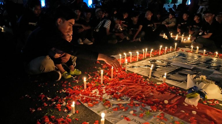 A man sprinkles flowers during a candle light vigil for the victims of Saturday's soccer riots, in Jakarta, Indonesia. (Dita Alangkara/AP)