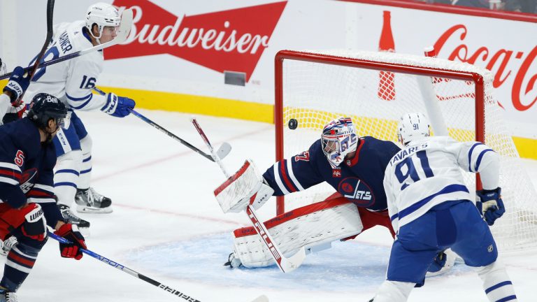 Toronto Maple Leafs' John Tavares (91) scores on Winnipeg Jets goaltender Connor Hellebuyck (37) during first period NHL action in Winnipeg. (John Woods/CP)