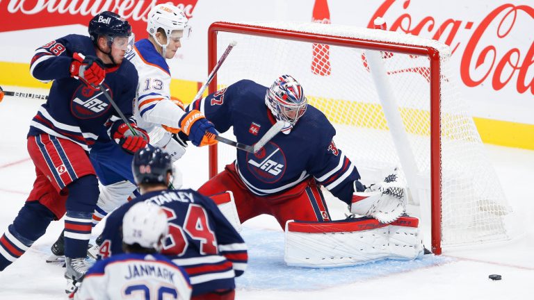 Winnipeg Jets goaltender Connor Hellebuyck (37) saves the shot from Edmonton Oilers' Jesse Puljujarvi (13) as Jets’ Nate Schmidt (88) defends during third period pre-season NHL action in Winnipeg, Saturday, October 1, 2022. (John Woods/CP) 