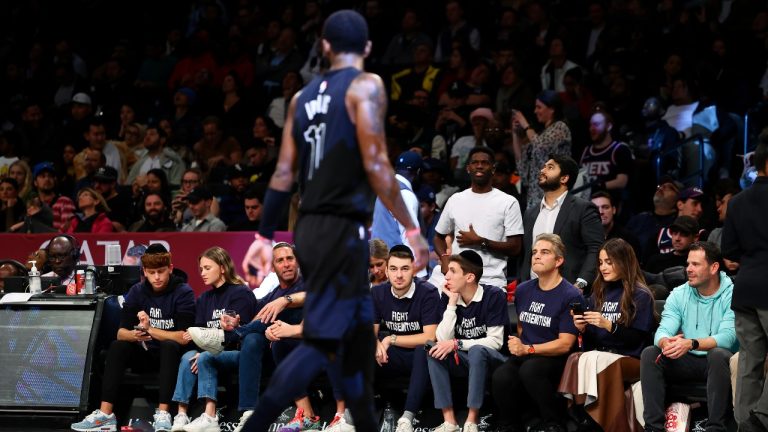 Fans with matching shirts look on as Brooklyn Nets guard Kyrie Irving (11) walks by during the first half of an NBA basketball game against the Indiana Pacers, Monday, Oct. 31, 2022, in New York. (Jessie Alcheh/AP Photo)