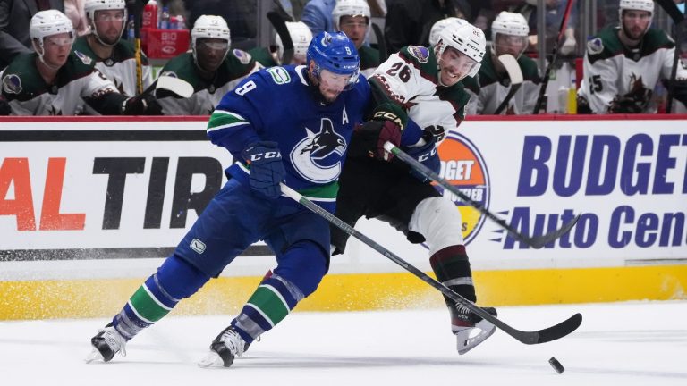 Vancouver Canucks' J.T. Miller (9) and Arizona Coyotes' Laurent Dauphin (26) vie for the puck during the second period of a pre-season NHL hockey game in Vancouver, on Friday, October 7, 2022. (Darryl Dyck/CP)