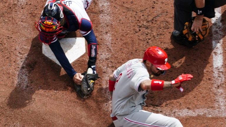 Philadelphia Phillies right fielder Nick Castellanos (8) scores against Atlanta Braves catcher Travis d'Arnaud (16) during the third inning in Game 1 of a National League Division Series baseball game, Tuesday, Oct. 11, 2022, in Atlanta.