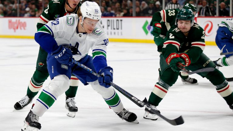 Vancouver Canucks right wing Vasily Podkolzin (92) and Minnesota Wild defenseman Calen Addison (2) compete for the puck during the second period of an NHL hockey game Thursday, Oct. 20, 2022, in St. Paul, Minn. (Andy Clayton-King/AP)