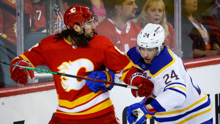 Buffalo Sabres' Dylan Cozens, right, checks Calgary Flames' Christopher Tanev during second period NHL hockey action in Calgary, Friday, March 18, 2022.THE CANADIAN PRESS/Jeff McIntosh 