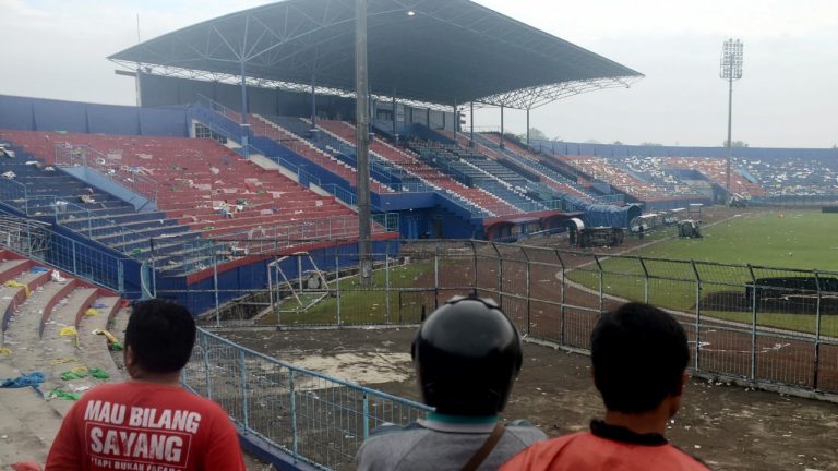 People examine the damage following a soccer match stampede at the Kanjuruhan Stadium in Malang, East Java, Indonesia, Sunday, Oct. 2, 2022. Panic at an Indonesian soccer match after police fired tear gas to to disperse supporters invading the pitch left over 100 people dead, mostly trampled to death, police said Sunday. (Hendra Permana/AP)