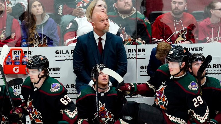 Arizona Coyotes head coach André Tourigny, top, watches the scoreboard as he stands behind Coyotes' Matias Maccelli (63), Nathan Smith, middle, and Barrett Hayton (29) during the third period of an NHL hockey game against the Carolina Hurricanes Monday, April 18, 2022, in Glendale, Ariz. The Hurricanes won 5-3. (Ross D. Franklin/AP) 