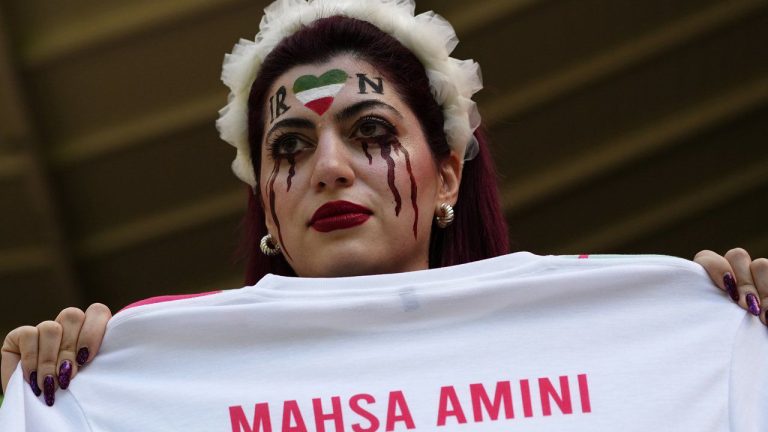 A woman holds a jersey with the name of Mahsa Amini, a woman who died while in police custody in Iran at the age of 22, as she takes her place in the stands ahead of the World Cup group B soccer match between Wales and Iran, at the Ahmad Bin Ali Stadium in Al Rayyan, Qatar, Friday, Nov. 25, 2022. (Pavel Golovkin/AP)