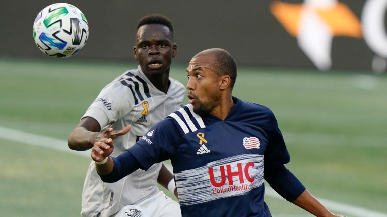 Montreal Impact's Karifa Yao, left, and New England Revolution's Teal Bunbury, right, keep their eyes on the ball during the first half of an MLS soccer match, Wednesday, Sept. 23, 2020, in Foxborough, Mass. The Vancouver Whitecaps picked up Canadian defender Yao in Major League Soccer's re-entry draft on Thursday. (CP/AP -Steven Senne)