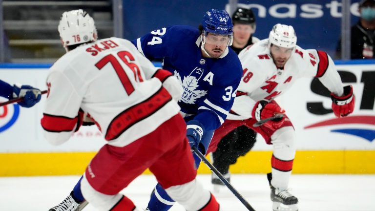 Toronto Maple Leafs centre Auston Matthews (34) moves the puck around Carolina Hurricanes defenceman Brady Skjei (76) during second period NHL hockey action in Toronto, Monday, Feb. 7, 2022. (Frank Gunn/THE CANADIAN PRESS)