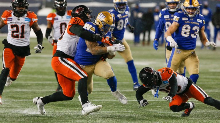 Winnipeg Blue Bombers' Brady Oliveira (20) is tackled by BC Lions' Mathieu Betts (90) as he makes a first down during the second half of CFL western final action in Winnipeg, Sunday, Nov. 13, 2022. (John Woods/CP)