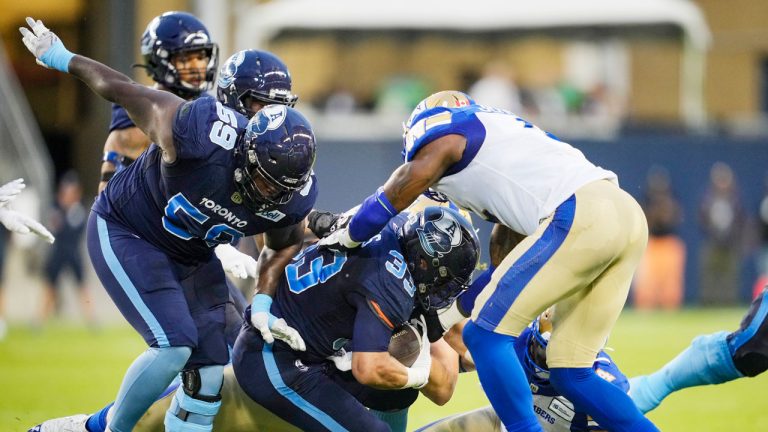 Toronto Argonauts' Andrew Harris, centre, runs the ball with teammate Dejon Allen, left, against Winnipeg Blue Bombers' Willie Jefferson, right, during the first half of CFL football action. (Mark Blinch/CP)