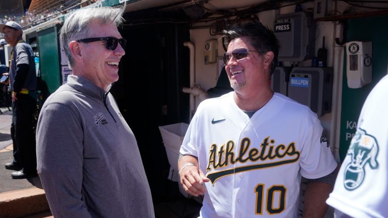 Oakland Athletics executive vice president of baseball operations Billy Beane, left, laughs while talking with former player Scott Hatteberg as the Athletics honor their 2002 team before a baseball game between the Athletics and the New York Yankees in Oakland, Calif., Sunday, Aug. 28, 2022. (Jeff Chiu/AP)