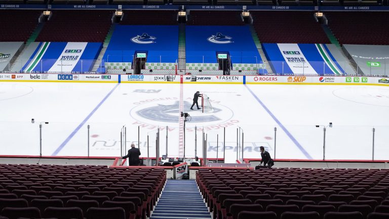 An arena worker removes the net from the ice after the Vancouver Canucks and Calgary Flames NHL hockey game was postponed due to a positive COVID-19 test result, in Vancouver, on Wednesday, March 31, 2021. (Darryl Dyck/CP)