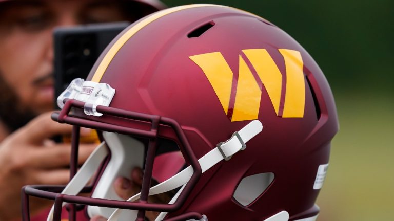 A fan takes a picture of a Washington Commanders helmet before practice at the team's NFL football training facility, Friday, July 29, 2022 in Ashburn, Va. (AP Photo/Alex Brandon)