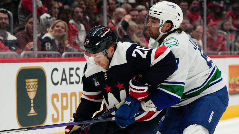 Washington Capitals right wing Connor Brown (28) tries to control the puck as Vancouver Canucks defenseman Noah Juulsen, right, defends during the first period of an NHL hockey game, Monday, Oct. 17, 2022, in Washington. (AP Photo/Jess Rapfogel)