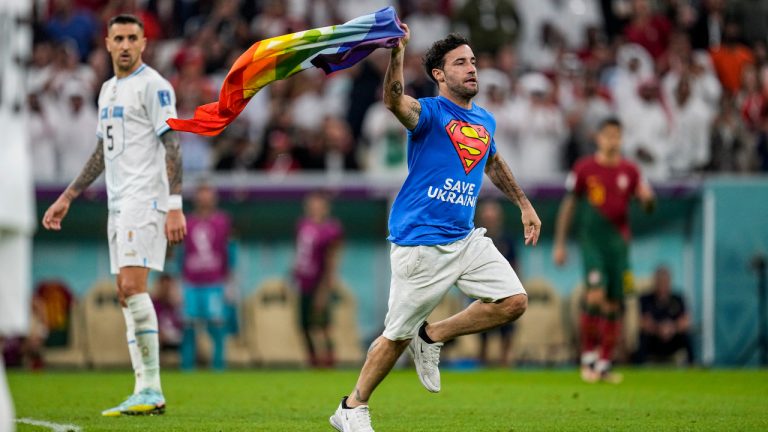 A pitch invader runs across the field with a rainbow flag during the World Cup group H soccer match between Portugal and Uruguay, at the Lusail Stadium in Lusail, Qatar, Monday, Nov. 28, 2022. (Abbie Parr/AP) 