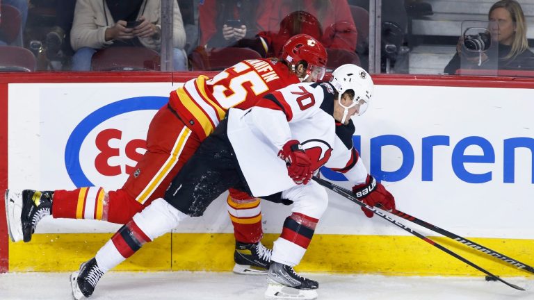 New Jersey Devils' Jesper Boqvist, right, battles for the puck against Calgary Flames' Noah Hanifin during second period NHL hockey action in Calgary, Saturday, Nov. 5, 2022. (Larry MacDougal/THE CANADIAN PRESS)