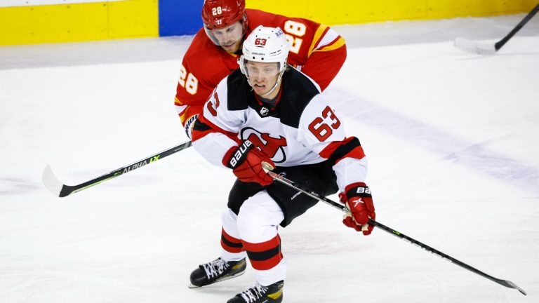 New Jersey Devils' Jesper Bratt, right, beats Calgary Flames' Elias Lindholm to the puck during second period NHL hockey action in Calgary, Wednesday, March 16, 2022. (Jeff McIntosh/CP)