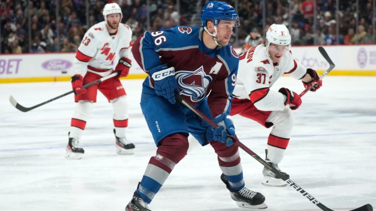 Colorado Avalanche right wing Mikko Rantanen, front, drives past Carolina Hurricanes right wing Andrei Svechnikov, right, during the third period of an NHL hockey game Saturday, Nov. 12, 2022, in Denver. (David Zalubowski/AP)