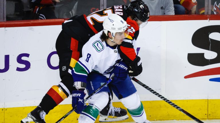 Vancouver Canucks forward Conor Garland, left, checks Calgary Flames defenceman MacKenzie Weegar during second period NHL hockey action in Calgary, Wednesday, Dec. 14, 2022. (Jeff McIntosh/CP)