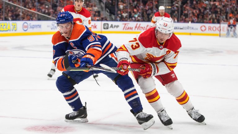 Calgary Flames' Tyler Toffoli (73) and Edmonton Oilers' Connor McDavid (97) battle for the puck during second period pre-season action in Edmonton on Friday, September 30, 2022. (Jason Franson/CP)