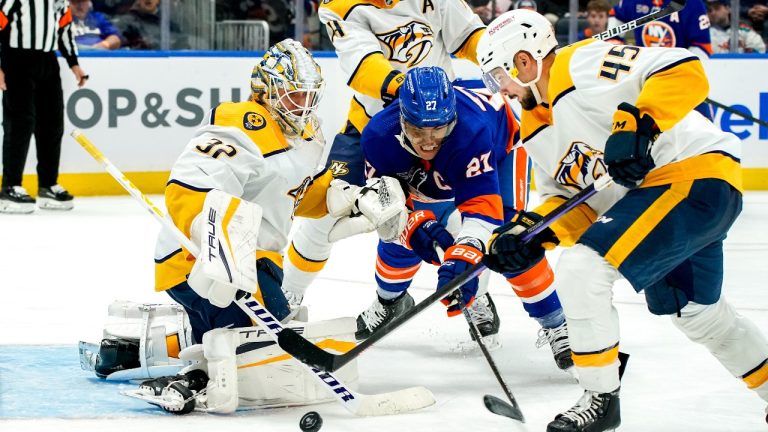 New York Islanders left wing Anders Lee (27) and Nashville Predators defenceman Alexandre Carrier (45) fight for the puck as Predators goaltender Kevin Lankinen guards the goal during the second period of an NHL hockey game, Friday, Dec. 2, 2022, in Elmont, N.Y. (Julia Nikhinson/AP Photo)