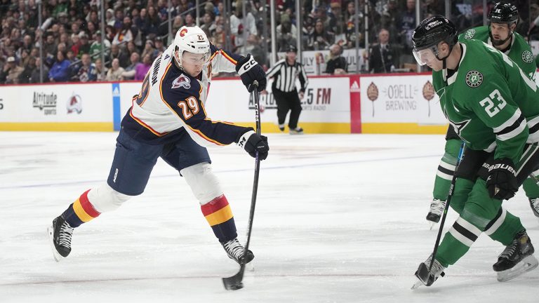 Colorado Avalanche centre Nathan MacKinnon, left, shoots past Dallas Stars defenseman Esa Lindell for a goal in the first period of an NHL hockey game Saturday, Nov. 26, 2022, in Denver. (David Zalubowski/AP)