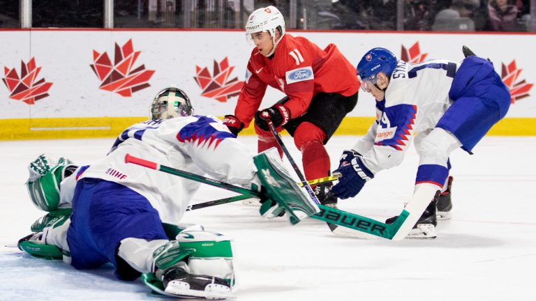 Slovakia goaltender Adam Gajan makes a save on Switzerland's Jeremy Jabola as Slovakia's Adam Sykora defends during second period IIHF World Junior Hockey Championship hockey action in Moncton, N.B., on Saturday, Dec. 31, 2022. (Ron Ward/CP)