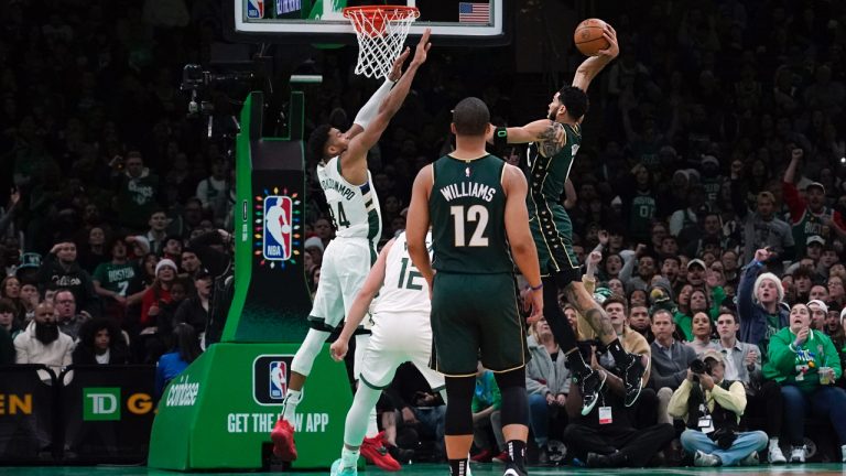 Boston Celtics forward Jayson Tatum (0) drives in for the slam dunk over Milwaukee Bucks forward Giannis Antetokounmpo (34) during the first half of an NBA basketball game, Sunday, Dec. 25, 2022, in Boston. (Mary Schwalm/AP)