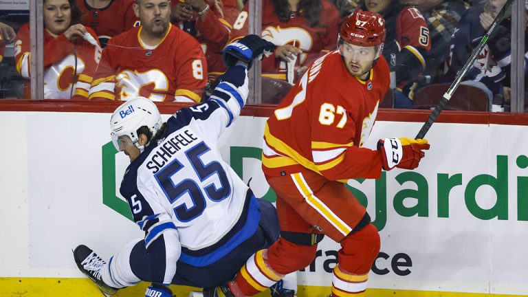 Winnipeg Jets forward Mark Scheifele, left, is checked by Calgary Flames forward Radim Zohorna during first period NHL pre-season hockey action in Calgary, Friday, Oct. 7, 2022.(Jeff McIntosh/CP)