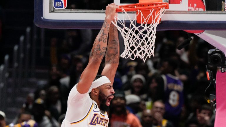 Los Angeles Lakers forward Anthony Davis, left, dunks against Washington Wizards centers Daniel Gafford (21) and Kristaps Porzingis (6) during the second half of an NBA basketball game, Sunday, Dec. 4, 2022, in Washington. The Lakers won 130-119. (AP Photo/Jess Rapfogel)