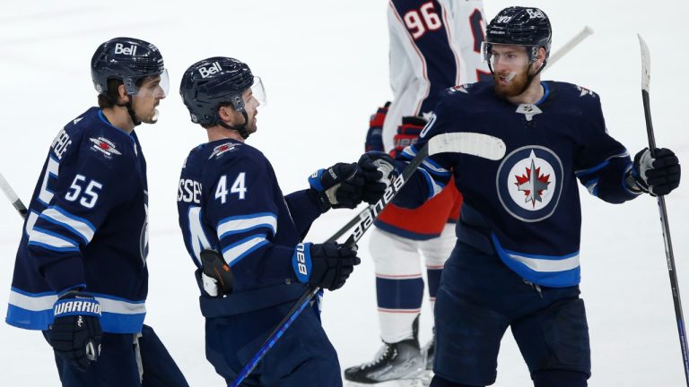 Winnipeg Jets' Mark Scheifele (55), Josh Morrissey (44) and Pierre-Luc Dubois (80) celebrate Morrissey's goal against the Columbus Blue Jackets during second period NHL action in Winnipeg, Friday, March 25, 2022. (John Woods/CP)