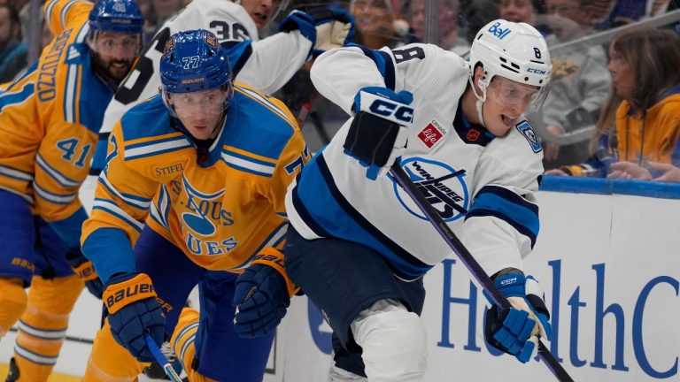 Winnipeg Jets' Saku Maenalanen (8) and St. Louis Blues' Niko Mikkola (77) chase after a loose puck along the boards during the first period of an NHL hockey game Thursday, Dec. 8, 2022, in St. Louis. (AP Photo/Jeff Roberson)